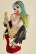 Young woman holding guitar over colored background