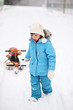 Photo: Little girl is pulling her snow scooter with a toy Little girl is pulling her snow scooter with a toy