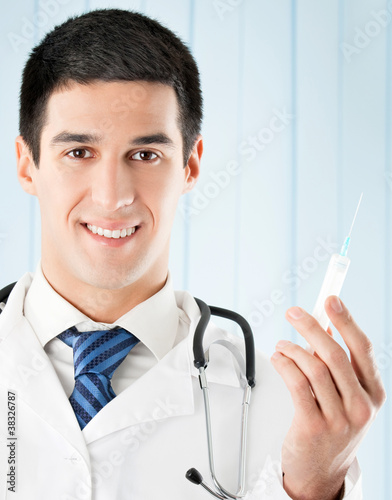 Photo: Happy doctor with syringe at office Happy doctor with syringe at office