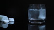 hand of man throws an aspirin into a glass of water