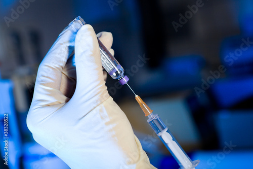 Photo: Scientist using syringe sucking vaccine, gloves Scientist using syringe sucking vaccine, gloves