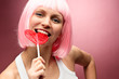 Young pink blondie with valentine lollipop on a pink background