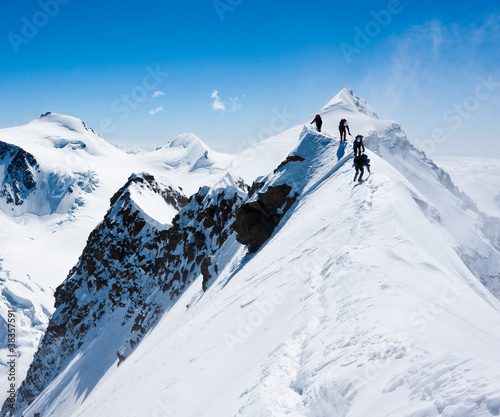 Photo: Climbers balancing in blizzard on a narrow ridge Climbers balancing in blizzard on a narrow ridge