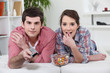 Young couple watching TV with a remote control