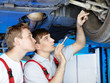 Motor mechanic and apprentice inspecting the engine of a car