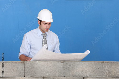 Foto: Engineer inspecting a construction blueprint Engineer inspecting a construction blueprint