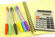 Old calculator and color pens on the yellow writing-book Old calculator and color pens on the yellow writing-book