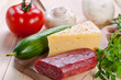 Photo: Sausage and cheese with vegetables on cutting board. Sausage and cheese with vegetables on cutting board.