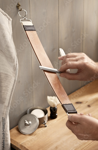 Photo: A man carefully stropping his straight razor A man carefully stropping his straight razor