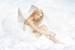 Young woman as angel sitting on clouds
