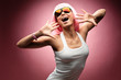 Young girl in pink wig and glasses dancing on a pink background