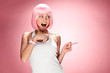 Young girl in pink wig showing for camera across pink background