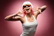 Young girl in pink wig and glasses dancing on a pink background