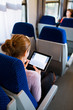 Young woman using her tablet computer while traveling by train