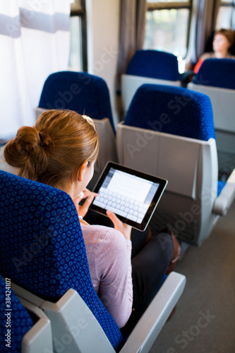 Foto: Young woman using her tablet computer while traveling by train Young woman using her tablet computer while traveling by train