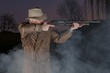 man with cowboy hat, long leather coat and riot gun