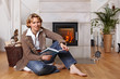 blond lady reading a book in front of a fireplace