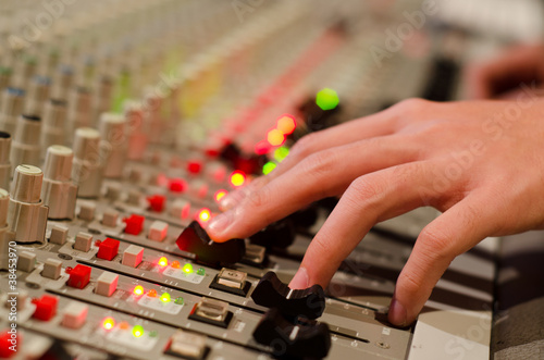 Photo: sound engineer's hand moving on sound mixing board sound engineer's hand moving on sound mixing board