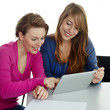 Two young girls learning together with touchpad at school
