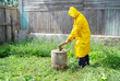 An elderly man in a yellow raincoat with an ax