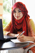 Beautiful muslim woman wearing red scarf ready to write