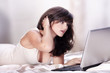 Junge Frau auf dem Bett surft mit Laptop Junge Frau auf dem Bett surft mit Laptop