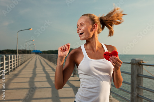 Photo: Beautiful woman in sunset light on a pier with watermelon heart Beautiful woman in sunset light on a pier with watermelon heart