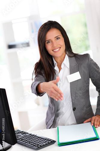 Photo: Portrait of beautiful smiling hostess giving handshake Portrait of beautiful smiling hostess giving handshake
