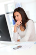 Foto: Beautiful office worker in front of desktop computer Beautiful office worker in front of desktop computer