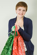 Cute young redhead woman holding red and green shopping bags