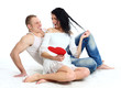Happy young adult couple with red heart on the floor Happy young adult couple with red heart on the floor