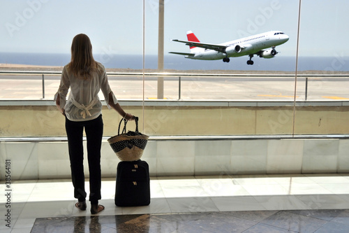 Photo: Girl at the airport window looking to the ocean Girl at the airport window looking to the ocean