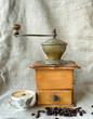 Ancient coffee grinder with grains and cup of coffee Ancient coffee grinder with grains and cup of coffee