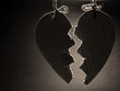 Broken paper heart hanging on rope. Dark sepia style.