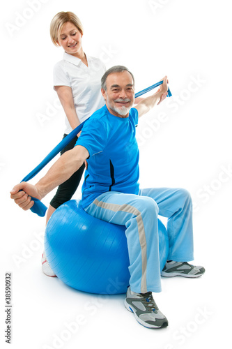 Photo: Senior man doing fitness exercise with help of trainer Senior man doing fitness exercise with help of trainer