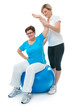 Senior woman doing fitness exercise with help of trainer in gym