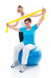 Senior woman doing fitness exercise with help of trainer in gym