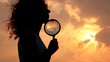 woman holds magnifier and puts it to chin against sky and sun