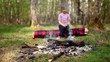 Little girl sits on log and watch at bonfire burn