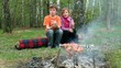 Boy and girl sit on log, bot hold glass and girl eat candy Boy and girl sit on log, bot hold glass and girl eat candy