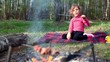 Little girl, sit on grass cover by plaid and eats kebab