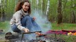 Woman sit and rotate skewer with fresh meat under embers