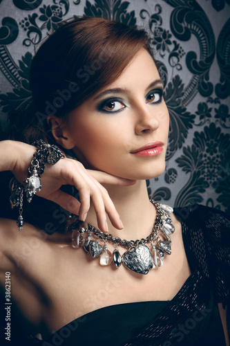 Photo: Portrait of pretty young woman with beads and bangle Portrait of pretty young woman with beads and bangle