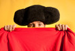 Bullfighter afraid with big montera hidden behind cape humor