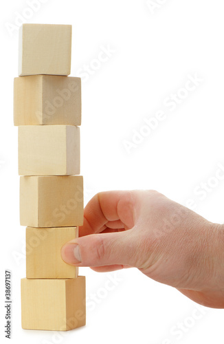 Photo: The hand establishes a wooden cube. The hand establishes a wooden cube.