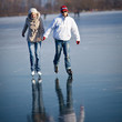 Photo: Couple ice skating outdoors on a pond on a lovely winter day Couple ice skating outdoors on a pond on a lovely winter day