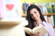 smiling female student with book in hands in a bookstore - model