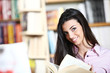 smiling female student with book in hands in a bookstore - model