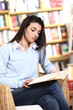 female student reading a book in library