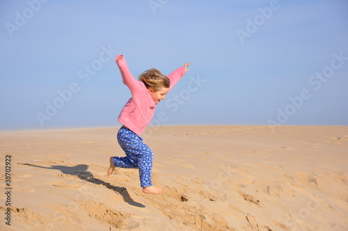 Photo: Fillette sautant d'une dune Fillette sautant d'une dune